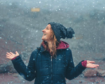 Side view of young woman with arms outstretched standing outdoors