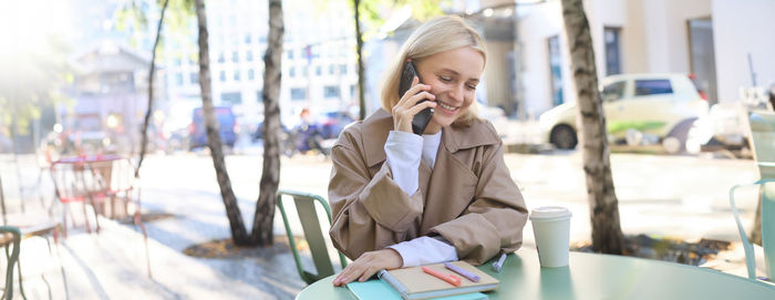 Portrait of young woman using mobile phone in office