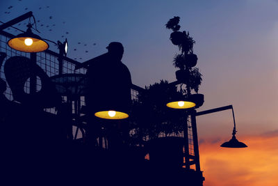 Low angle view of illuminated lights against sky at sunset