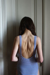 Rear view of woman standing against door at home