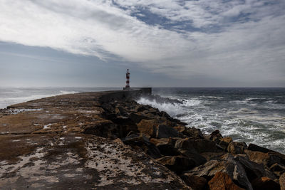 Lighthouse by sea against sky