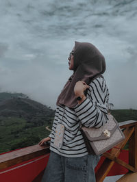 Side view of woman looking at sea against sky