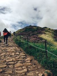 Rear view of man standing on mountain against sky