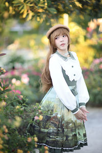 Portrait of young woman standing against plants