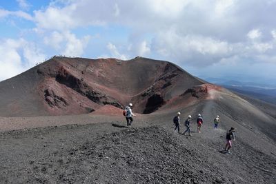 People walking on mountain road against sky