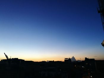 Silhouette cityscape against clear sky at sunset
