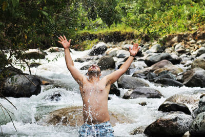 Man splashing water in stream at forest