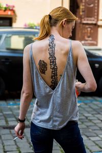 Rear view of woman with tattoo on back standing on footpath