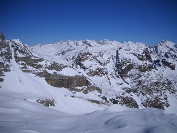 Scenic view of snowcapped mountains against clear blue sky