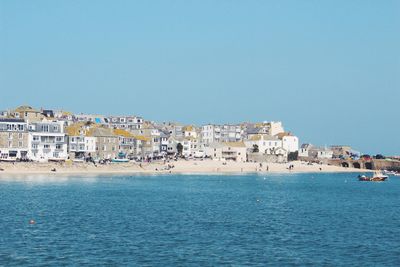 Scenic view of sea and townscape against clear blue sky