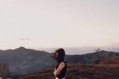 Woman with arms raised against sky