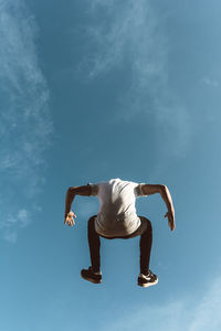 Rear view of man jumping against sky
