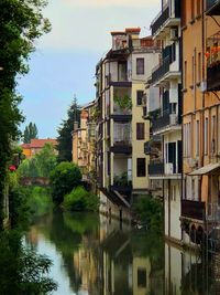 Buildings by river in city against sky