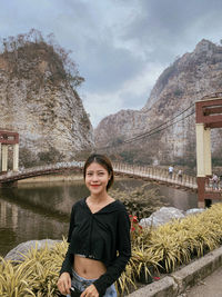 Portrait of young woman standing against mountain