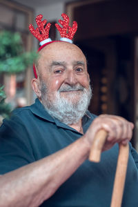 Funny old man with reindeer ears holding a walking stick