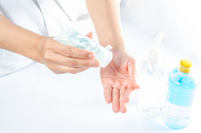 Close-up of woman hand holding bottle over white background