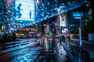 Illuminated city street during rainy season at night