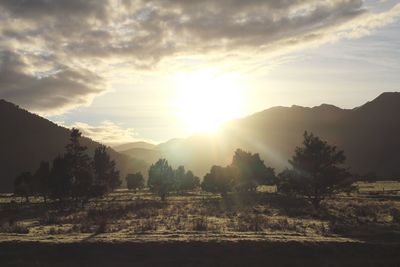 Sun shining through clouds over landscape