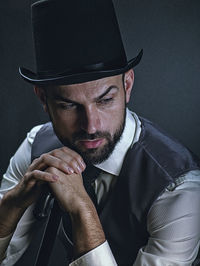 Portrait of man wearing hat against black background