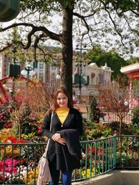 Portrait of smiling young woman standing against trees