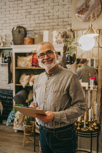 Portrait of senior male entrepreneur holding clipboard while standing at home decor store