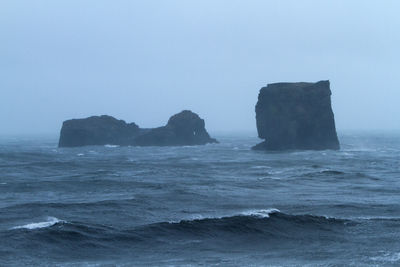 Rock formation in sea against clear sky