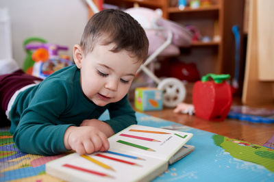 Young toddler boy looking at books and playing in his room