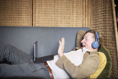 Senior man in headphones having video call on tablet