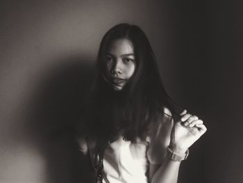 Portrait of young woman standing against wall