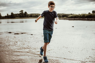 Full length of boy running on lakeshore
