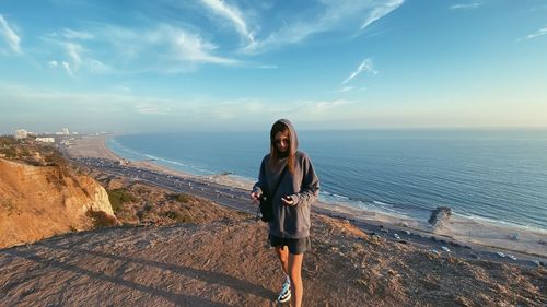 Side view of woman standing on beach against sky