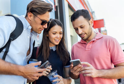 Uk, london, portobello road, three friends looking at cell phone