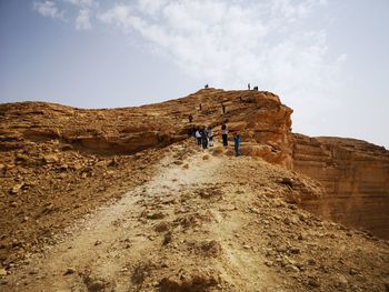 People on rock formations against sky