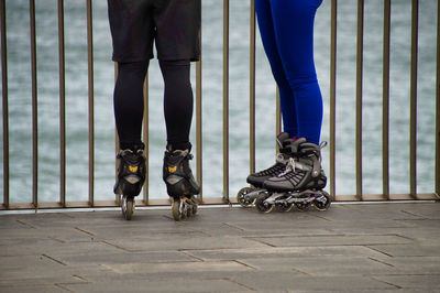 Low section of friends inline skating on promenade