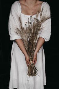 Midsection of woman standing against black background