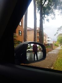 Reflection of man on side-view mirror of car