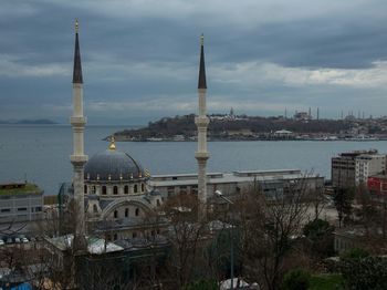 City at waterfront against cloudy sky