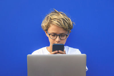 Boy using phone against blue background