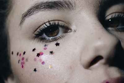 Close-up portrait of young woman with star shape make-up on face