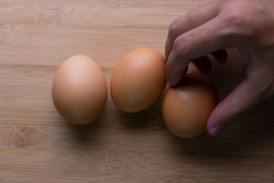 Close-up of hand holding eggs on table