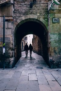 Rear view of people walking on footpath amidst buildings in city