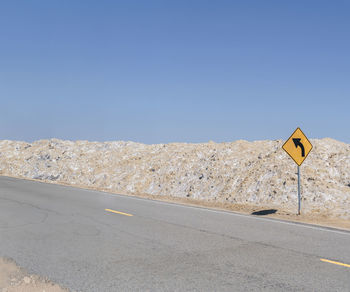 People on road against clear blue sky