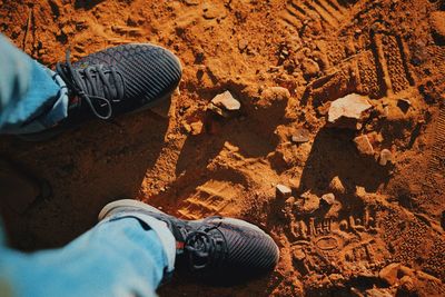 Low section of man standing on sand