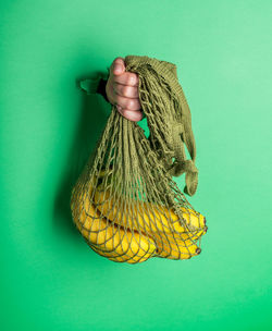 Close-up of hand holding yellow leaf against blue background