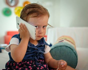 Cute girl talking on mobile phone while sitting at home