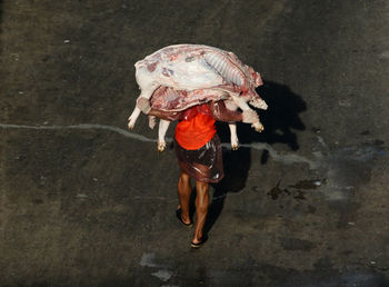 High angle view of man carrying raw meat while walking on road