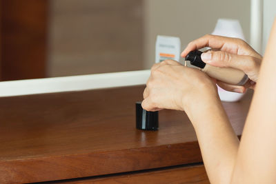 Cropped hands of person using mobile phone on table