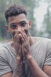 Portrait of smiling young man covering face