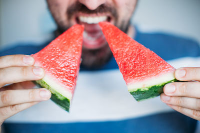 Midsection of man eating watermelons