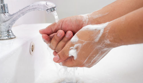 Cropped image of hand touching water in bathroom